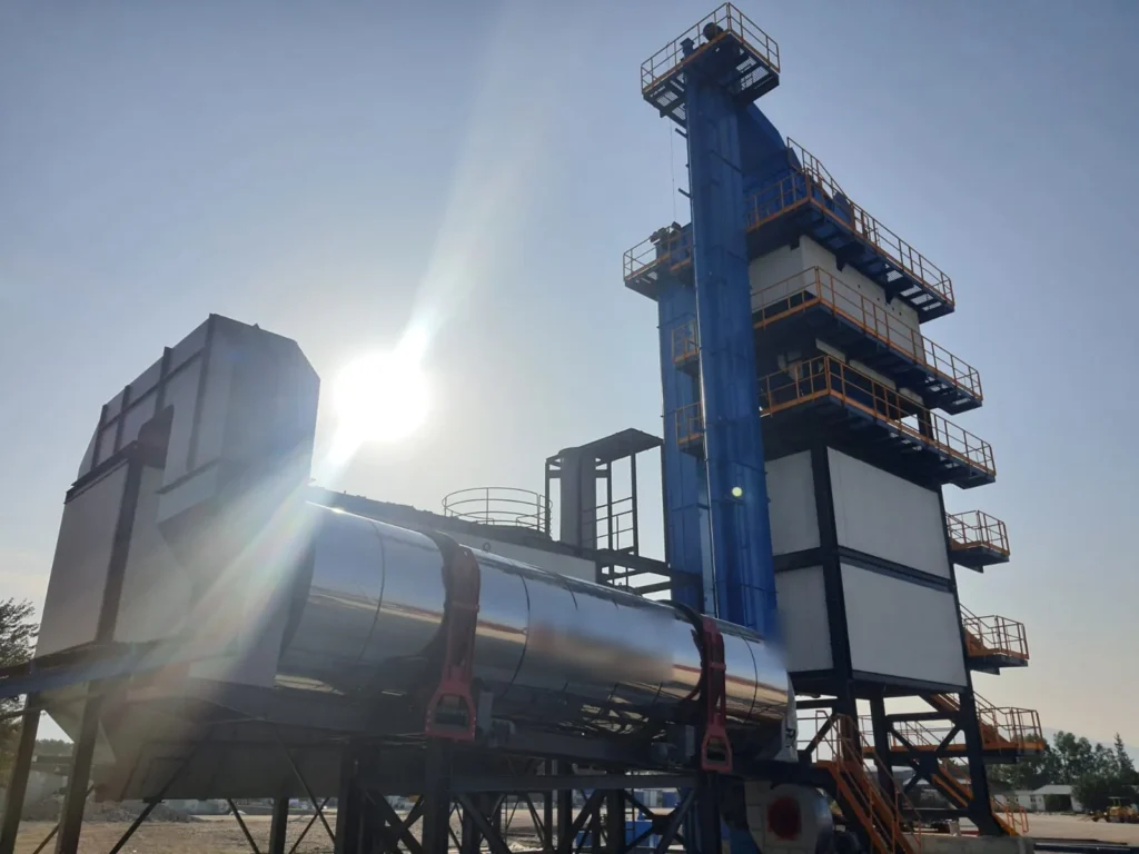 Asphalt batch plant with insulated rotary dryer drum, baghouse filter and hot aggregate elevator beside the mixing tower