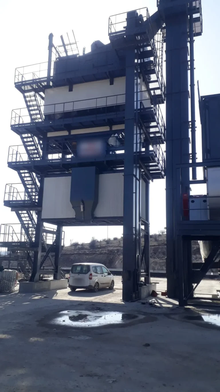 Truck loading lane under an asphalt batch plant mixing tower, where hot mix asphalt is discharged into trucks